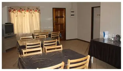 a dining room with a table and chairs and a television at Confortable farmhouse in Limpopo Province in Lephalale