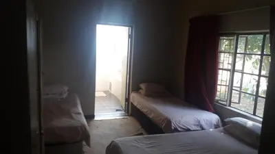 a room with two beds and a door to a window at Homely room in peaceful and comfortable old farmhouse in Lephalale