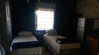 two twin beds in a room with a window at Old farmhouse for 3 in Limpopo Province in Lephalale