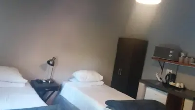 a room with two beds and a desk with a lamp at Old farmhouse for 3 in Limpopo Province in Lephalale
