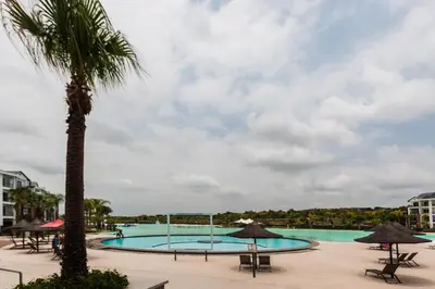 a pool with a palm tree and tables and umbrellas at #Alimama Spaces Blyde Haven in Pretoria