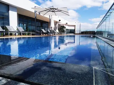 a pool with chairs and an umbrella on top of a building at Menlyn Apartment - Black Marble in Pretoria