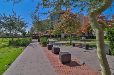 a park with benches and trees and a building at 301 Menlyn Maine Trilogy Apartment in Pretoria