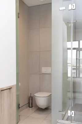 a bathroom with a toilet and a glass shower at Menlyn Apartment - Marble Print in Pretoria