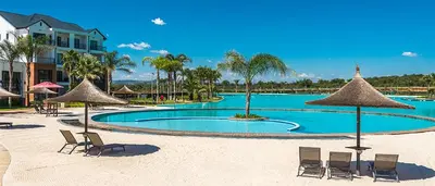 a swimming pool with chairs and umbrellas on a beach at Insaka 1 The Blyde Crystal Lagoon Experience in Pretoria
