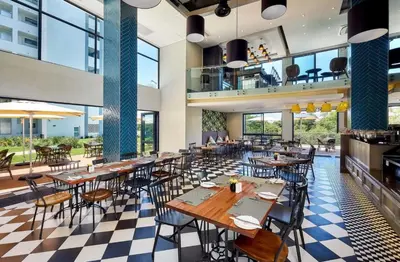 a restaurant with tables and chairs and large windows at Menlyn apartment with ensuit Regency Hotel in Pretoria