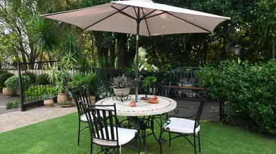 a table and chairs with an umbrella in a yard at LUXURY EN-SUITE KING ROOM @ 4 STAR GUEST HOUSE in Middelburg