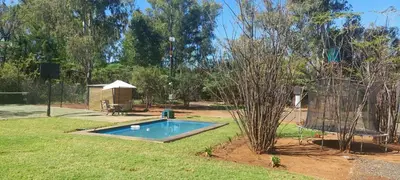 a small swimming pool in a yard with a tree at Vulture's View 1 in Hartbeespoort