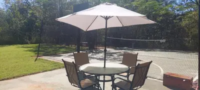 a table and chairs with an umbrella on a tennis court at Vulture's View 3 in Hartbeespoort