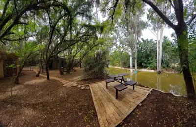 a picnic table sitting on a wooden platform next to a river at Vulture's View 2 in Hartbeespoort