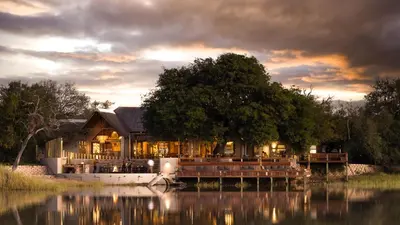 a house sitting on the water in front of a lake at Simbavati Waterside in Klaserie Private Nature Reserve