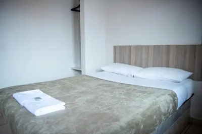 a bedroom with a bed with white sheets and pillows at Ecomotel Kempton Park in Kempton Park