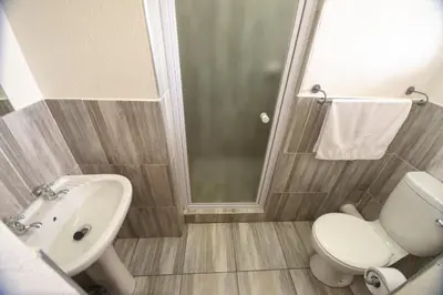 a bathroom with a toilet and a sink and a shower at Ecomotel O.R.Tambo in Kempton Park