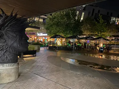 a mall with a statue of a head in a city at night at Menlyn Maine Residences - Superior king - Paris apartment in Pretoria