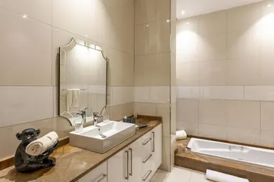 a bathroom with a sink and a mirror and a tub at Lejwe La Metsi Self-Catering Villa in Bela-Bela