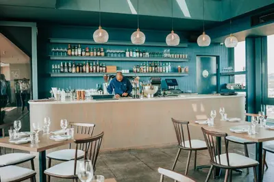 a man standing at the bar of a restaurant at 703 Menlyn Maine Residences, The Trilogy in Pretoria