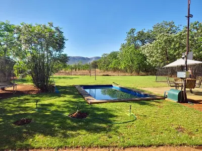 a pool in a yard with a table and an umbrella at Vulture's View 9 in Hartbeespoort