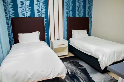 two beds in a room with blue and white walls at TINDLOVU GUESTHOUSE in Nelspruit