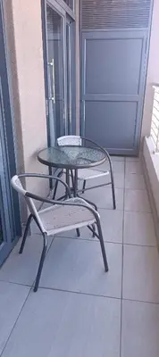 a table and a chair on a balcony at Menlyn Maine Trilogy Apartment 1010 in Pretoria
