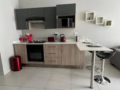 a kitchen with black cabinets and a white counter top at Mellow-Suites Apartments - 31 - WIFI and Netflix in Midrand