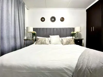 a bedroom with a large bed with white sheets and pillows at Siena Sun Luxury Suites 5 in Midrand