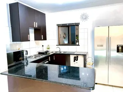 a kitchen with black countertops and a stainless steel refrigerator at Midrand Siena Sun Luxury Suites 3 with water reserve in Midrand