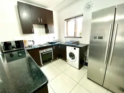 a kitchen with a refrigerator and a washing machine at Midrand Siena Sun Luxury Suites 3 with water reserve in Midrand