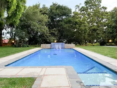 a swimming pool in the middle of a yard at Afrique134 Willow Tree Private Garden Suite in Pretoria