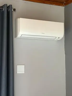 a white air conditioner in a room with a curtain at Blue Lotus Guest House Pta East-Solar power in Pretoria